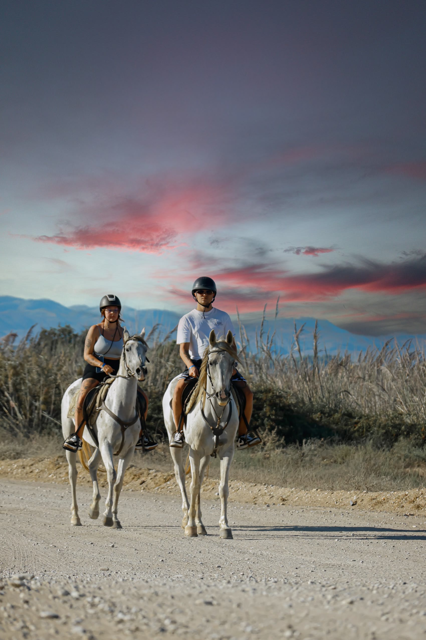 Two riders beneath a pink evening sky