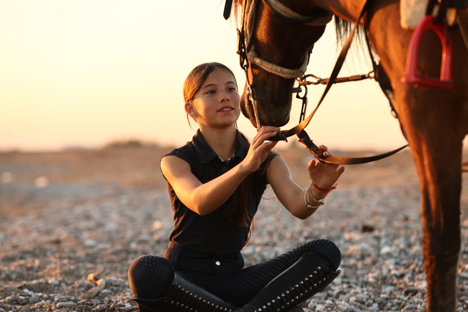 A young rider and her horse at sunset